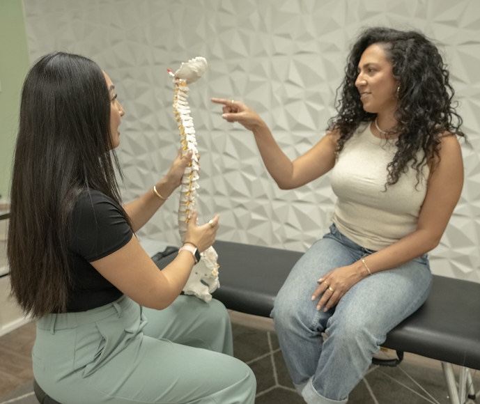 Dr. Lisa Ly explaining spinal alignment using a spine model during consultation